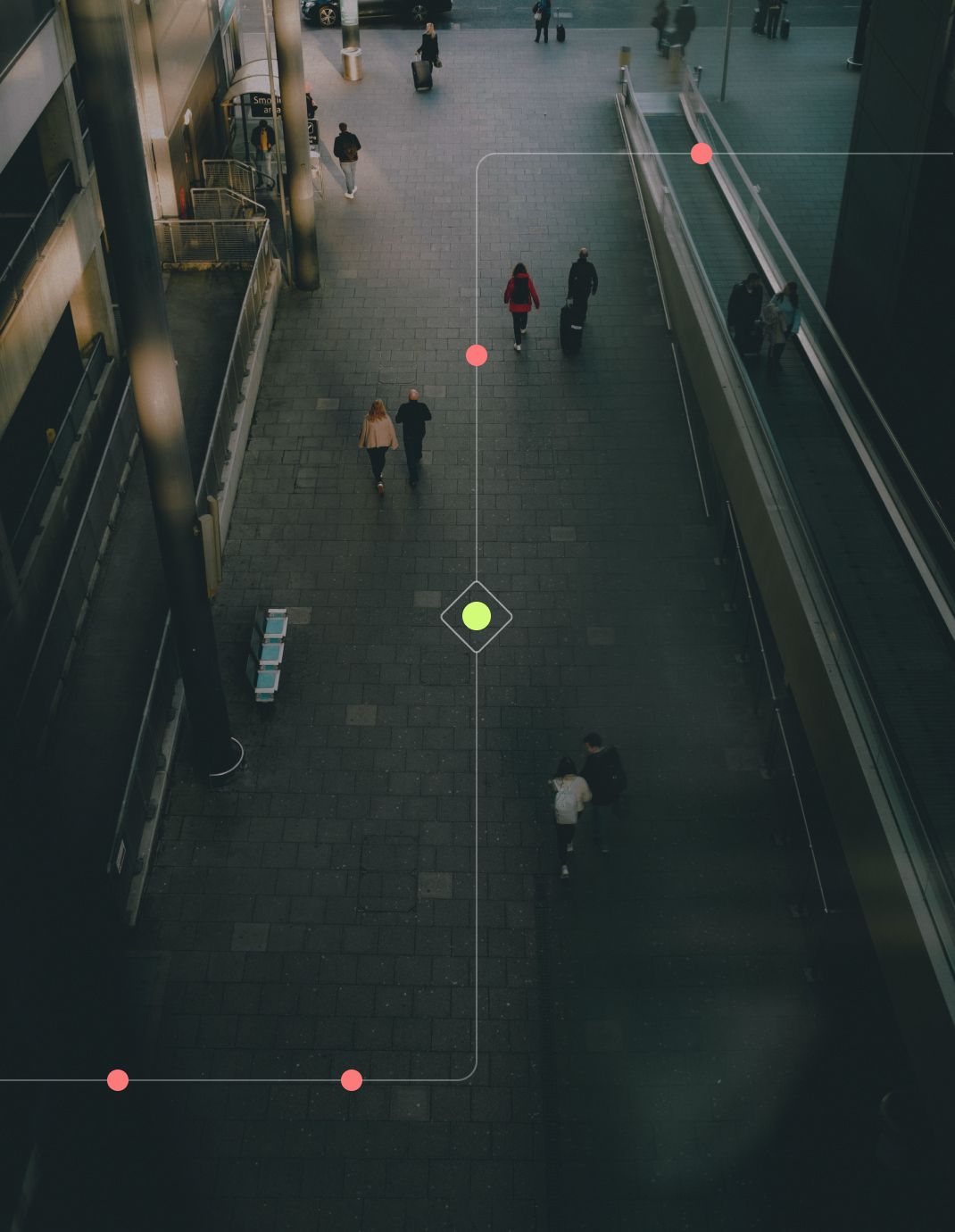 Aerial view of a busy urban walkway with people walking, featuring a green marker and red dots indicating points of interest.