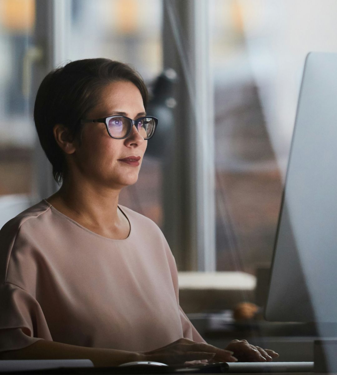 A person working at a computer in a well-lit office environment, focused on the screen.