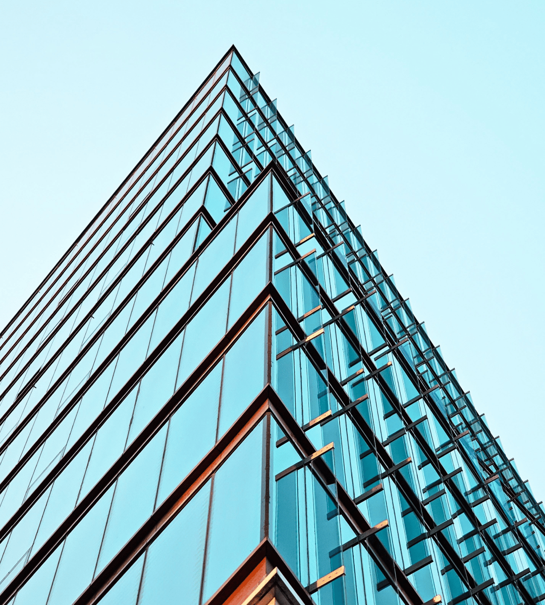 Modern office building with a sleek glass façade and angular design against a clear blue sky.