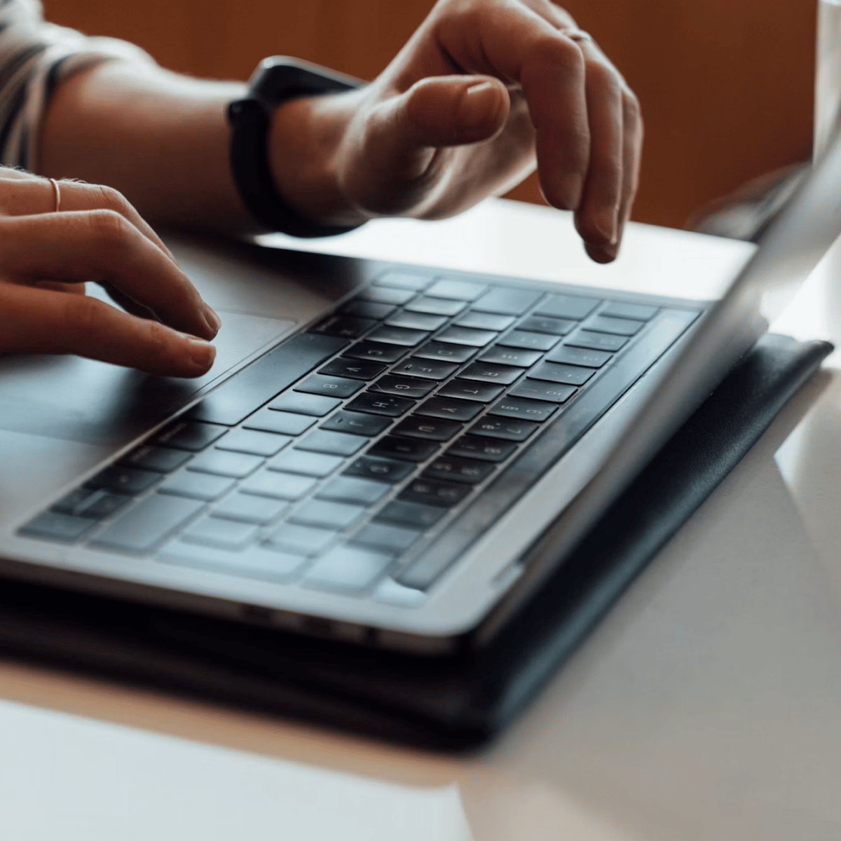 Hands typing on a laptop keyboard, with a focus on the keyboard and the hand position.
