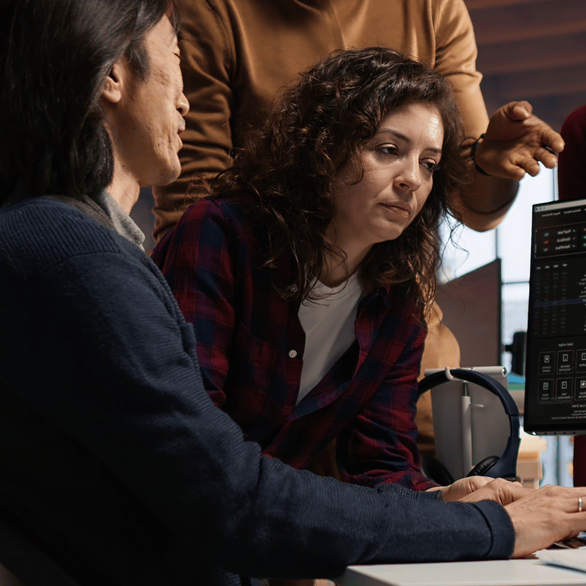 Team collaborating on a project, focused on a computer screen displaying data and analytics in a professional workspace.