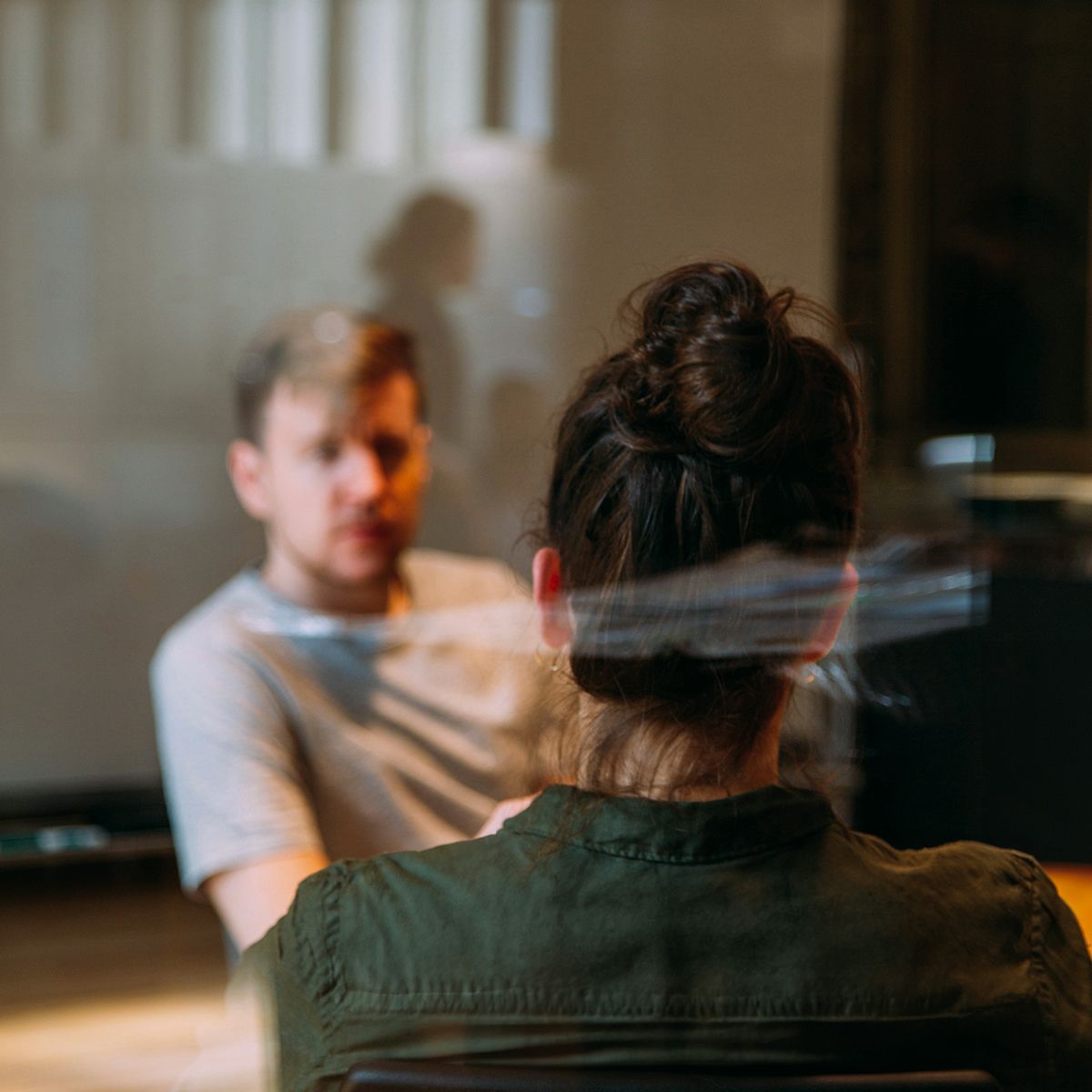 Two individuals engaged in a conversation, with one person in focus and the other partially obscured, reflecting a casual meeting setting.
