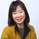 A person smiling in a yellow jacket against a light background.