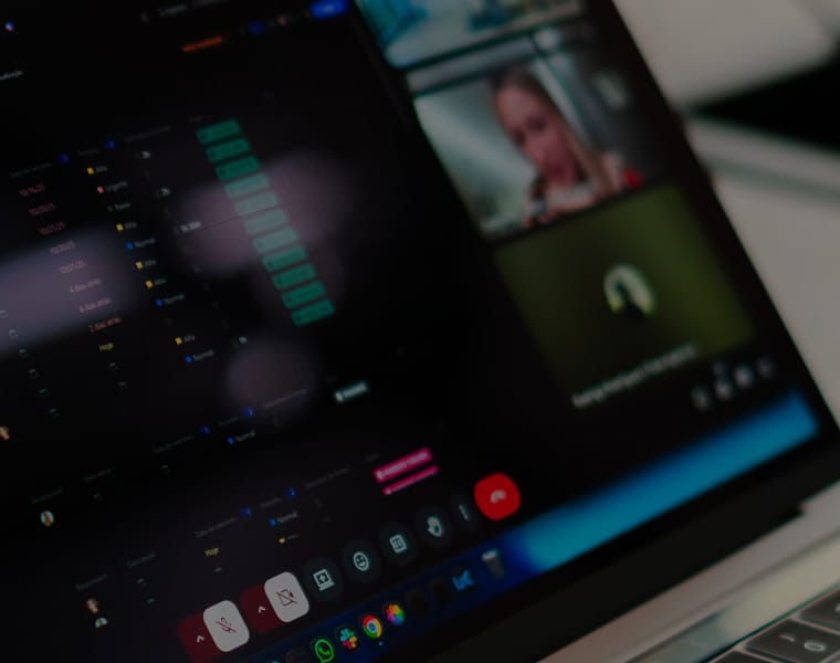 A close-up of a laptop screen displaying a video call interface with various participant windows and controls in a dark theme.