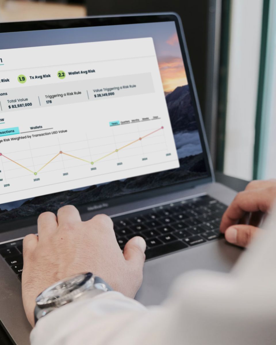 Dashboard displaying cryptocurrency transaction metrics, including total value, risk averages, and wallet analytics on a laptop screen.