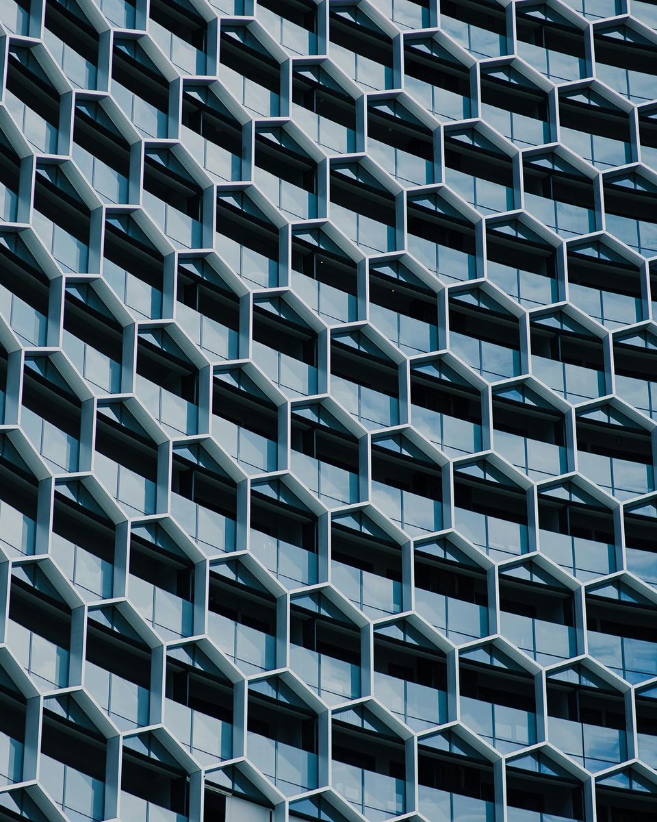 Geometric facade of a modern building featuring hexagonal windows in a repeating pattern with a blue and glass color scheme.